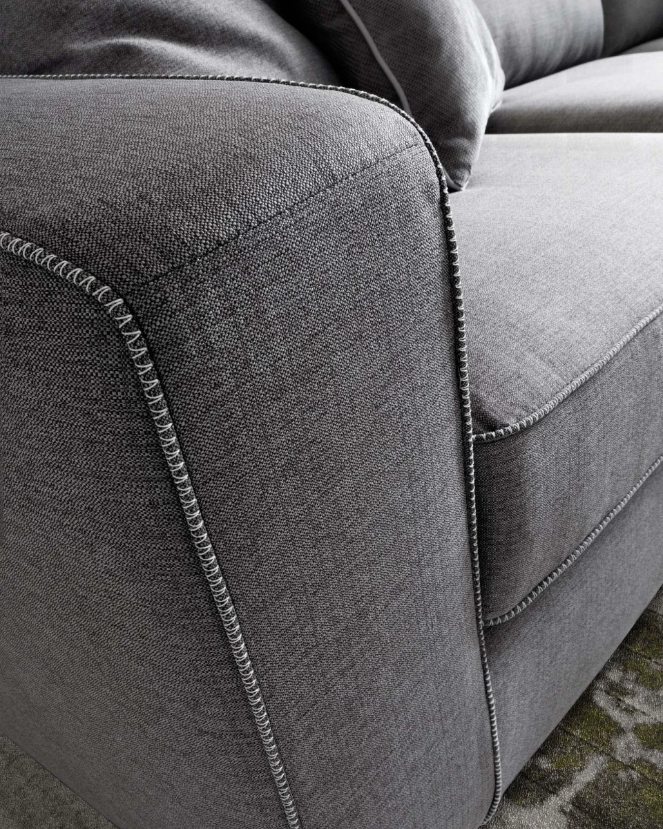 Magyster — Sofa with visible stitching and integrated side shelf.