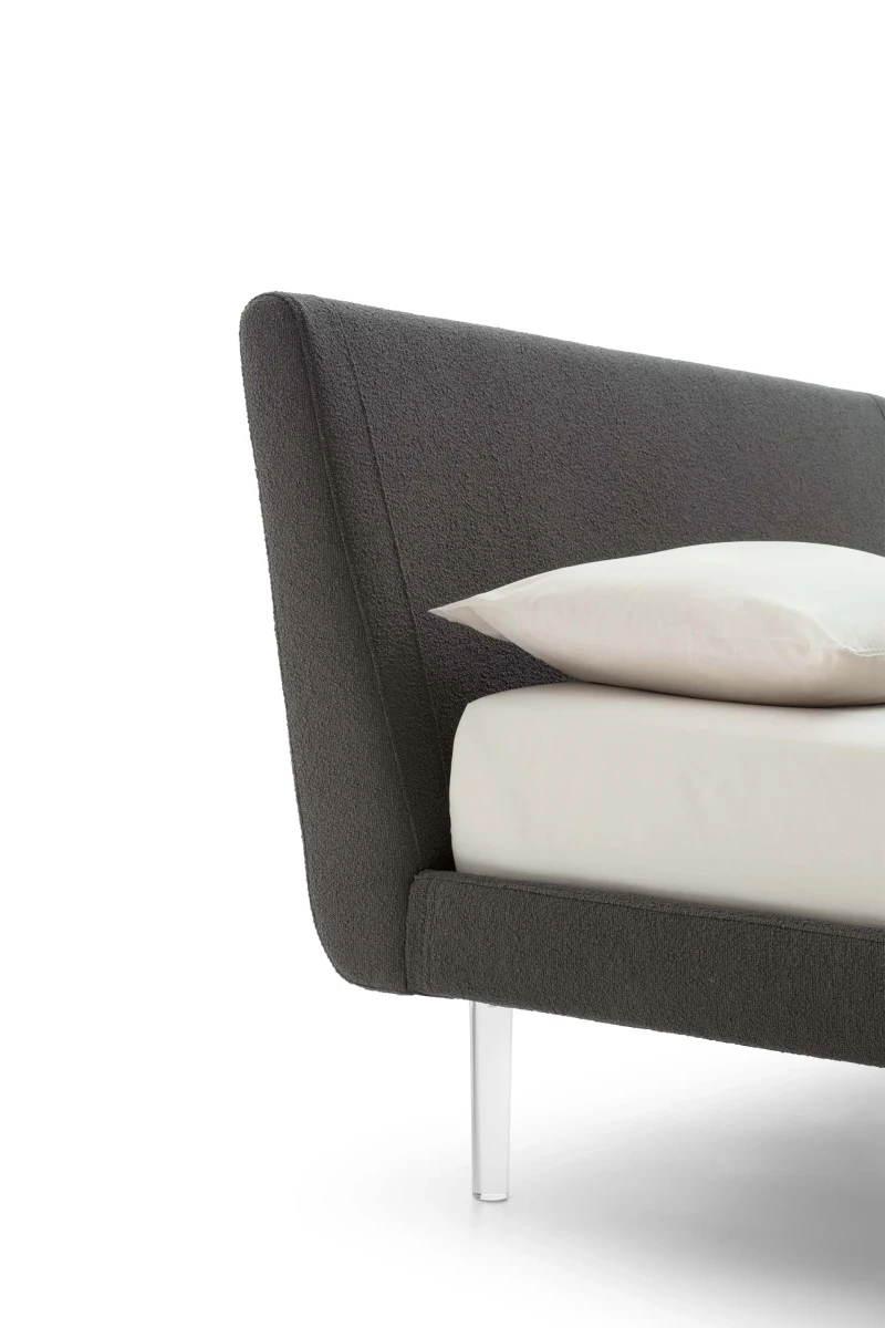 Metropolitan — Bed with a simple, slightly inclined upholstered headboard and subtle side stitching.