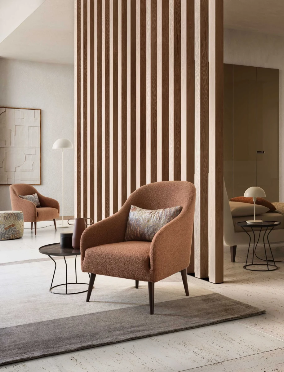 Adda — Simple armchair with soft, welcoming lines and high legs.