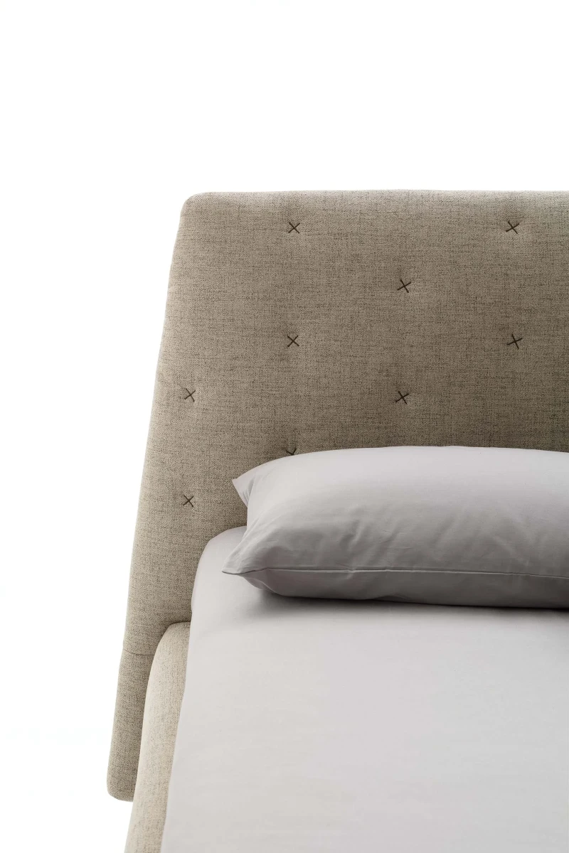 Atrium — Bed with quilted headboard featuring contrasting "X" stitching.