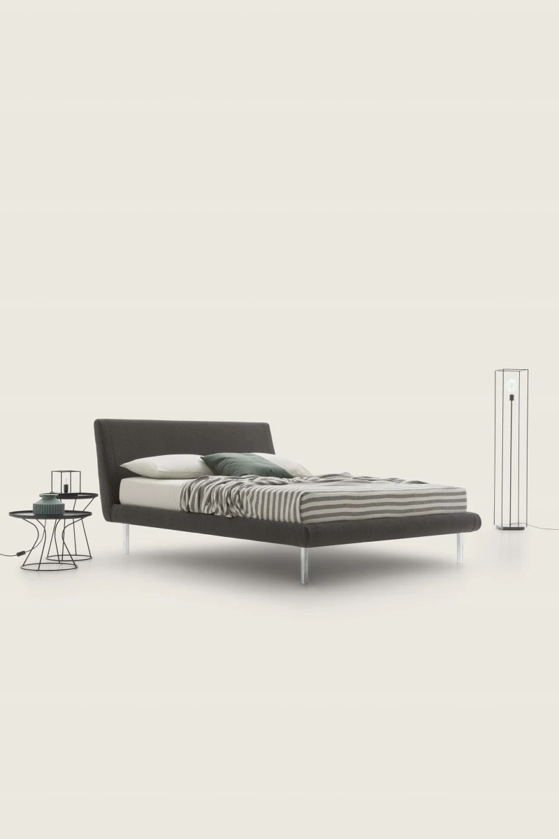 Metropolitan — Bed with a simple, slightly inclined upholstered headboard and subtle side stitching.