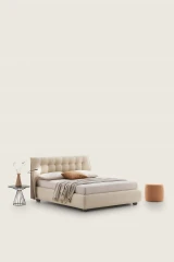 Guscio — Bed with a tufted headboard in a classic capitonne style.