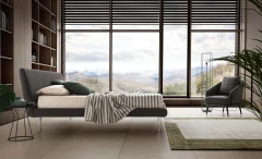 Metropolitan — Bed with a simple, slightly inclined upholstered headboard and subtle side stitching.