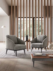 Lala — Modern, enveloping armchair with an outer shell featuring vertical quilting.