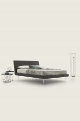 Metropolitan — Bed with a simple, slightly inclined upholstered headboard and subtle side stitching.