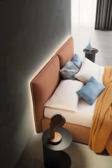 Allen — Comfortable bed with a headboard composed of large cushions with decorative piping.